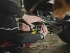 A mechanic is working on the underside of a car. Produktbild-Vorschau