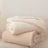 Two folded fluffy blankets are stacked on top of each other on a couch. Podgląd zdjęcia produktu