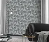 A living room scene with a patterned wallpaper, a floor lamp, a sofa, and a side table. Produktbild-Vorschau