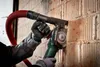 A person is using a wall chaser with a vacuum attachment to cut a groove into a brick wall. Produktbild-Vorschau
