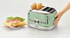 A hand is shown touching a green vintage toaster with toast popping out. A plate of sandwich ingredients is next to it. Produktbild-Vorschau