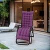 A purple cushion on a recliner chair on a patio, with another lounge chair in the background and a building with large windows behind. Náhled obrázku produktu