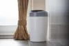A diaper pail next to a broom, with a tiled wall in the background. Voir les images du produit