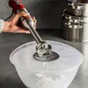 A hand holding a red and silver immersion blender over a clear bowl filled with white powder. Produktbild-Vorschau