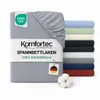 A folded fitted sheet is shown prominently, with a stack of other fitted sheets in various colors in the background. Produktbild-Vorschau