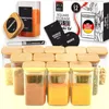 Set aus 12 quadratischen Glas-Gewürzgläsern mit Bambusdeckeln, einem weißen Kreidestift und schwarzen Etiketten für Gewürze wie Cayennepfeffer, Bourbon-Vanille und Ingwer Anteprima dell’immagine prodotto