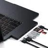 A close-up shot of a laptop with a docking station attached, showing various ports and accessories like USB drives and memory cards. Produktbild-Vorschau