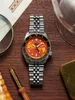A Seiko 5 Sports GMT watch is displayed on a wooden surface, surrounded by other items like a magnifying glass, a pen, and a glass. Podgląd zdjęcia produktu