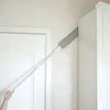 Weiß-grauer ausziehbarer Staubwedel, der in eine Ecke zwischen weißem Türrahmen und weißem Schrank reicht, von einer Hand gehalten Produktbild-Vorschau