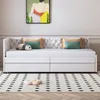 A white daybed with tufted headboard and storage drawers, decorated with pillows and a panda plush toy, placed in a room with a painting on the wall and a patterned rug on the floor. Produktbild-Vorschau
