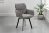 A gray upholstered chair with black legs is shown in a room with a potted plant. Produktbild-Vorschau