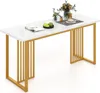 A white marble-effect rectangular dining table with gold metal legs, set against a white background. Decorative items like a magazine, fruit bowl, and a vase of flowers are placed on the table.