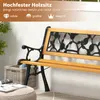 A close-up view of a wooden garden bench with decorative metalwork on the backrest, placed outdoors on a patio. Produktbild-Vorschau