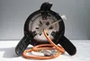 The underside of a portable gas stove with its attached orange gas hose and regulator. Produktbild-Vorschau