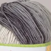 A close-up view of a ball of yarn with a gradient of gray tones and a section of white yarn visible. Produktbild-Vorschau