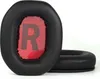 Two black ear pads for headphones are shown on a white background. One ear pad is in the foreground and shows a red mesh with a gray 'R' printed on it. The other ear pad is in the background and is viewed from the side. Podgląd zdjęcia produktu