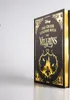 A black book with gold lettering and illustrations, standing upright on a reflective surface with a white background. Náhľad obrázku produktu