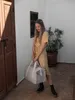 A woman stands in a doorway holding a large duffel bag. Produktbild-Vorschau