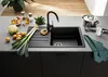 A kitchen counter with a black sink, faucet, and various kitchen items like vegetables, a pot, and a hand blender. Produktbild-Vorschau