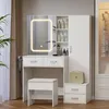 A white vanity table with a lighted mirror, drawers, shelves, and a stool, set in a room with curtains and a plant. Náhľad obrázku produktu