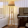 A floor lamp with shelves is placed next to a piano in a room with striped wallpaper. Podgląd zdjęcia produktu
