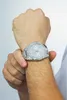 A man's wrist wearing a silver Guess watch. Náhled obrázku produktu