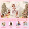 A young girl is sitting at a white vanity table with a mirror, holding a makeup brush. The scene is decorated for Christmas with two decorated trees and gift boxes. Náhled obrázku produktu