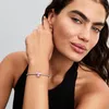 A woman is wearing a bracelet with a pink charm on her wrist. Podgląd zdjęcia produktu