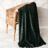 A dark green textured blanket draped over a wicker chair. Produktbild-Vorschau