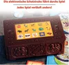 A close-up of a brown electronic treasure chest game with a screen displaying various icons, set on a surface with game cards. Produktbild-Vorschau