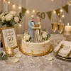 Tortenaufsatz goldenes Ehepaar auf dekorierter Jubiläumstorte zur goldenen Hochzeit, umgeben von Blumen, Kerzen und goldener Tischdeko. Anteprima dell’immagine prodotto