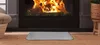 A hearth mat is placed in front of a fireplace with a fire burning. Produktbild-Vorschau