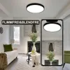 A living room scene with a ceiling light and a smartphone displaying a reflection of the light. Produktbild-Vorschau