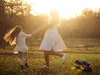 A mother and daughter are dancing in a field at sunset, with a boombox playing music. Produktbild-Vorschau