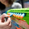 A close-up shot of a person loading darts into a toy gun. Produktbild-Vorschau