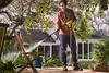 A man is pressure washing a wooden chair in a backyard setting. Produktbild-Vorschau