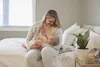 A woman is breastfeeding a baby on a bed. Podgląd zdjęcia produktu
