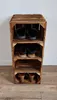 A tall, narrow shoe rack made of wooden crates against a white wall and on a wooden floor. Produktbild-Vorschau