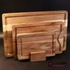 A set of wooden cutting boards of different sizes stacked on a stand, against a dark background. Produktbild-Vorschau