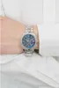 A person's wrist wearing a silver watch with a blue dial. Podgląd zdjęcia produktu