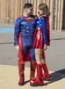 A couple dressed as Superman and Supergirl posing outdoors. Produktbild-Vorschau