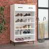 A white shoe cabinet with multiple shelves filled with shoes and slippers, placed against a brick wall. Anteprima dell’immagine prodotto