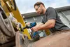 A man is using a cordless impact wrench on a piece of heavy machinery. Voir les images du produit