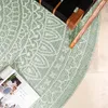 A close-up view of a round rug with a geometric pattern, partially covered by a magazine and a chair leg. Produktbild-Vorschau