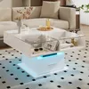 A modern white coffee table with integrated LED lighting and a glass top, placed in a living room setting next to a sofa. Produktbild-Vorschau