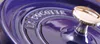 A close-up of a purple Staub cocotte lid with a gold knob. Náhled obrázku produktu