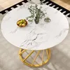 A round dining table with a marble-like top and a golden base, placed on a rug. Voir les images du produit