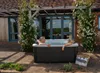 A couple relaxing in a hot tub on a patio, with a pergola and climbing roses in the background. Náhľad obrázku produktu