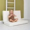 A young girl is sitting on a folded mat in front of a wall-mounted gym ladder. Anteprima dell’immagine prodotto