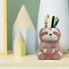 A ceramic sloth pen holder sits on a shelf with other desk accessories. Anteprima dell’immagine prodotto